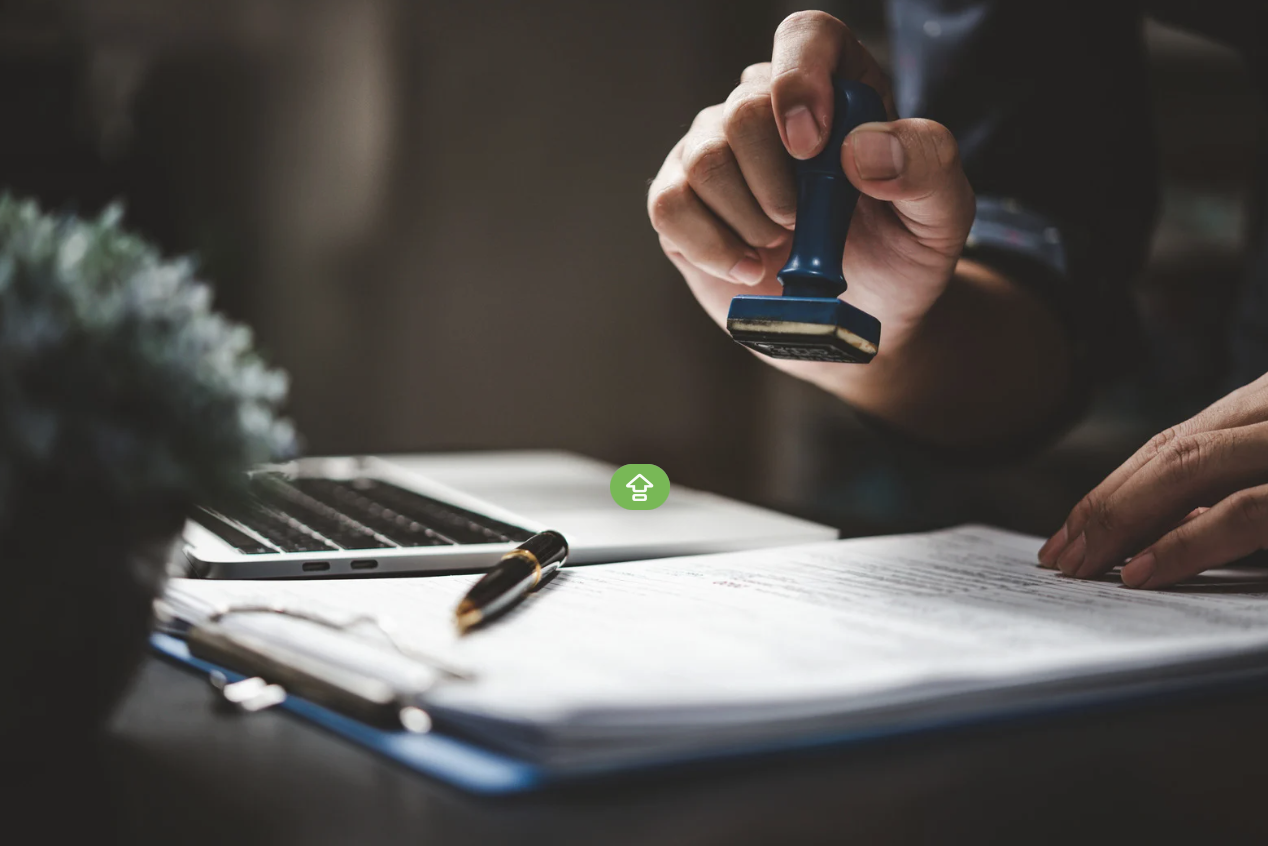 Document stamp beside a laptop and paperwork